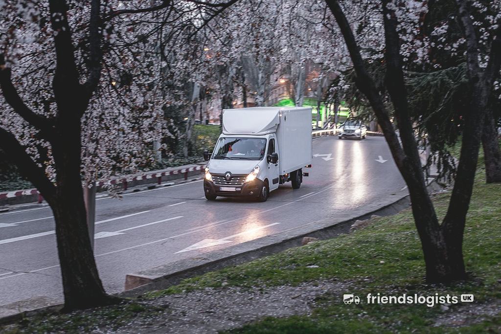 Removal lorry driving along a tree-lined road